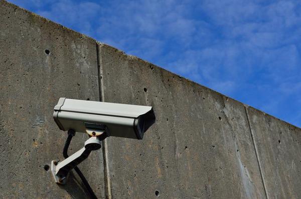 Foto: Eine Überwachungskamera an einer Betonmauer (ElasticComputeFarm, pixabay License)
